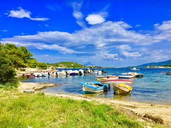 Boats moored at harbor against blue sky