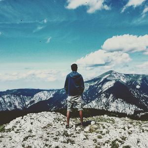 Woman standing on mountain against cloudy sky