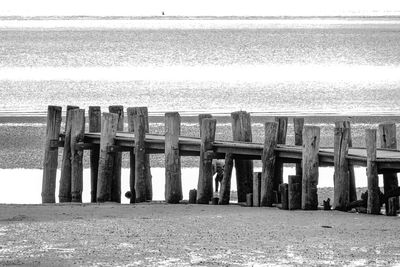 Wooden posts on beach by sea against sky