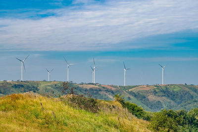 Wind turbines on field against sky