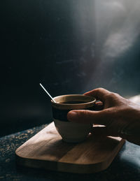 Cropped image of hand holding coffee cup on table