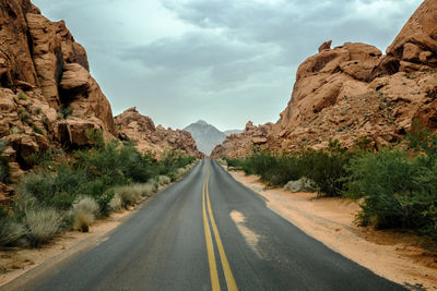 Road leading towards mountains against sky