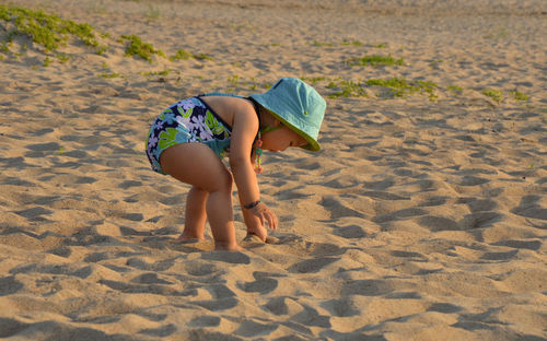 Cute girl playing in sand on shore of beach