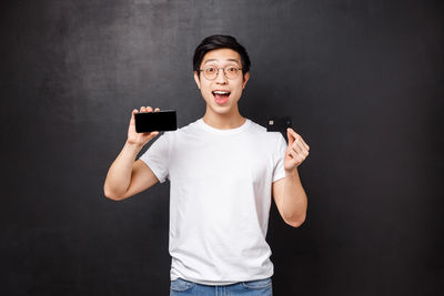 Man with credit card and smart phone against black background