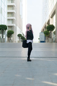 Full length of businesswoman wearing hijab and suit standing in city
