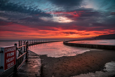 Scenic view of beach against cloudy sky during sunset