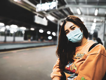 Portrait of beautiful woman standing on illuminated bus