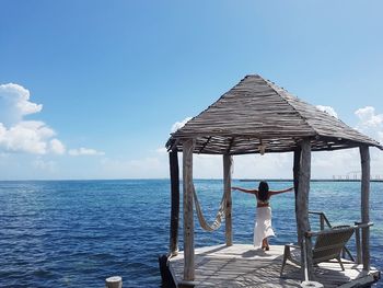 Woman standing by sea against blue sky