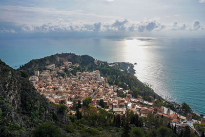 High angle view of townscape by sea against sky