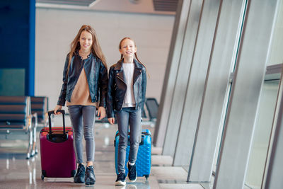 Sisters with suitcases walking in airport