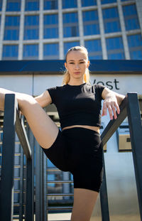 Woman leg stretching, flexible body stretching on street outdoor.