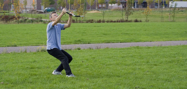 Full length of man flying kite while standing on grassy field