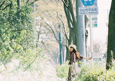 Woman standing by plants against trees