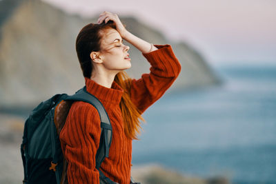 Young woman looking away while standing on shore