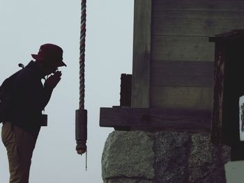 Side view of man photographing against sky