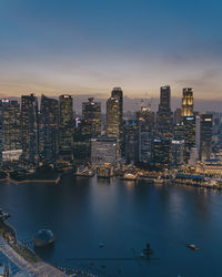 Illuminated buildings in city against sky during sunset