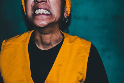 Portrait of young man standing against yellow wall