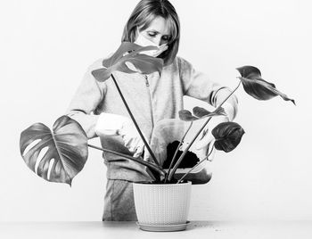 Young woman holding potted plant against white background