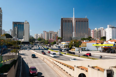 Vehicles on road amidst buildings in city against sky