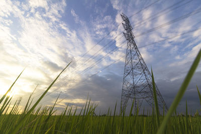 Low angle view of electricity pylon on field against sky