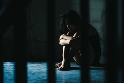 Side view of depressed woman sitting on floor