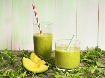 Smoothie in glasses and arugula on table