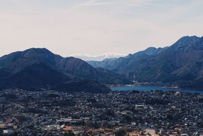 Aerial view of city by mountains against sky