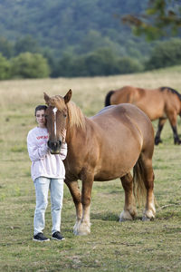 Girl with horse standing on field