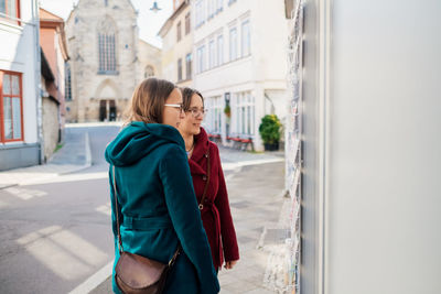 Woman standing on footpath in city