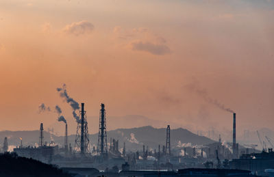 Smoke emitting from factory against sky during sunset