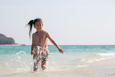 Girl standing at beach against sky