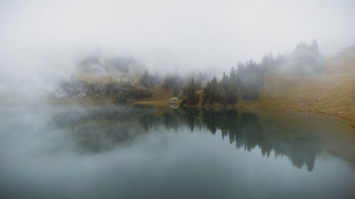 Scenic view of lake by trees against sky