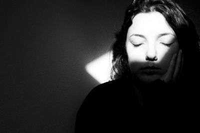 Close-up of young woman with eyes closed in darkroom