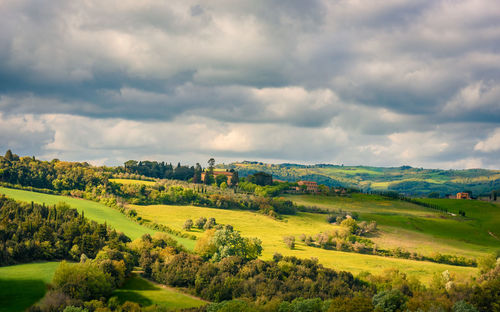 Scenic view of landscape in tuscany against cloudy sky
