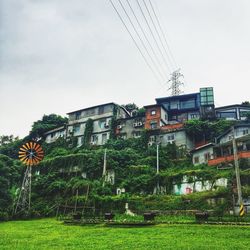 Trees and houses on field against sky