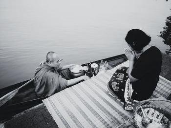 Rear view of men sitting by lake