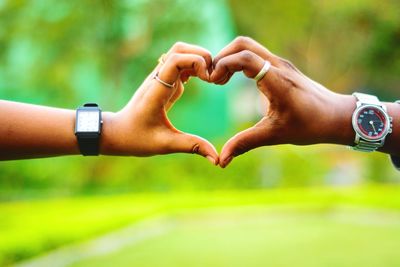 Cropped image of couple making heart shape with hands in park