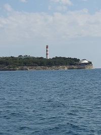 Lighthouse by sea against sky