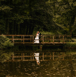 Newly wedded couple standing on old footbridge, boho, outdoors, wedding.