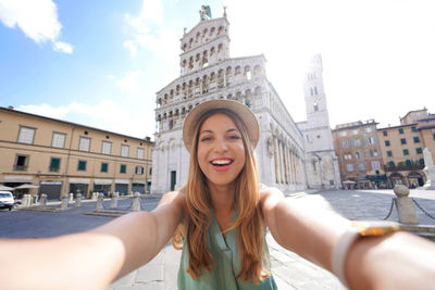 Smiling traveler girl takes selfie photo in the historic town of lucca, tuscany, italy