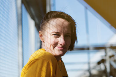 Portrait of smiling young woman with short hair against windows