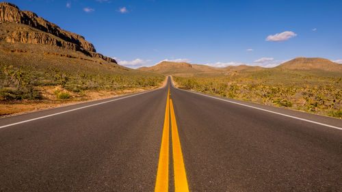 Road leading towards mountains against sky