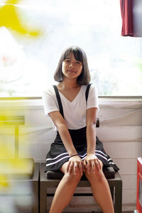 Portrait of smiling girl sitting on chair against window