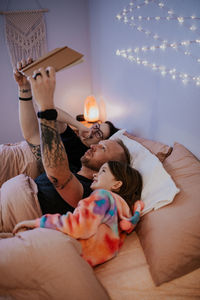 Vertical image of father laying in bed reading to kids