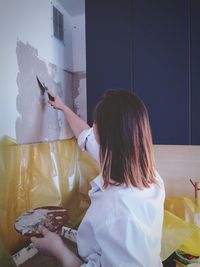 Rear view of woman painting wall