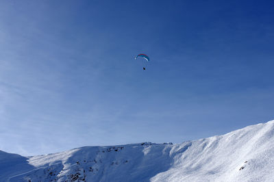 Low angle view of person paragliding against sky