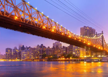 Illuminated bridge over river at night