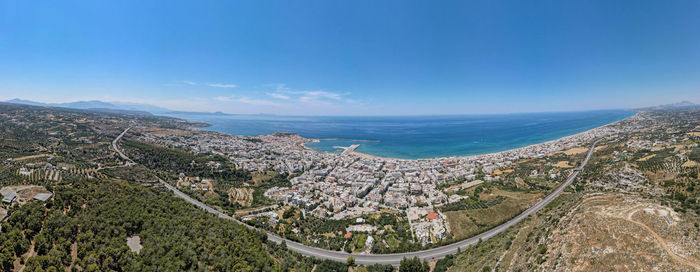 Panoramic view of sea and cityscape against blue sky