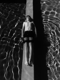 High angle view of boy resting on retaining wall in swimming pool