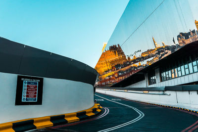 Illuminated road by building against sky